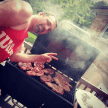 a man wearing a red shirt that says ' illinois ' on it is grilling meat