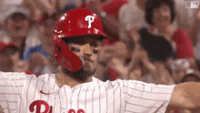 a baseball player wearing a red helmet with the letter p on it is standing in front of a crowd of people .