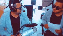 two men wearing headphones and sunglasses are talking into a microphone