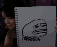 a woman is holding a drawing of a face that says ' i 'm sorry ' on it