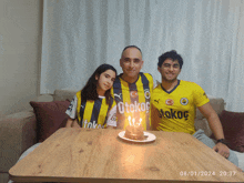 three people posing for a picture with one wearing a yellow shirt that says otokoc