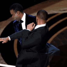 two men in tuxedos are dancing on stage