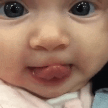 a close up of a baby 's face with his tongue out .