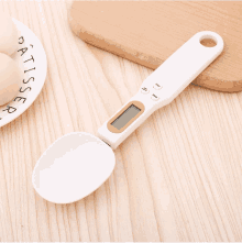 a digital measuring spoon is sitting on a wooden table