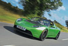 a green tesla model s is driving down the road