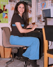 a woman is sitting in front of a computer with a poster on the wall that says ruiz