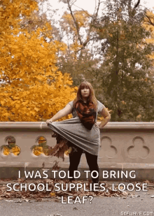 a woman is standing on a bridge holding a leaf and the caption says i was told to bring school supplies