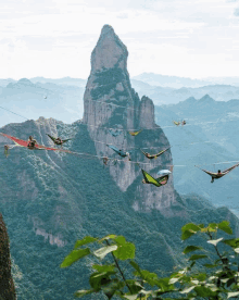 a group of people are laying in hammocks on a rope over a mountain