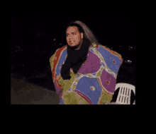 a man in a colorful blanket is standing next to a white chair