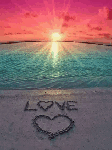 a heart is drawn in the sand on the beach with the word love written in the sand .