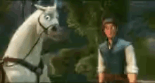 a man and a horse are standing next to each other in a forest .