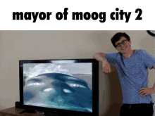 a man leans against a flat screen tv with the words mayor of moog city 2 above him