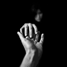 a black and white photo of a man holding a woman 's hand .