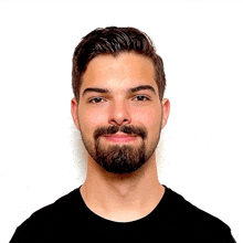 a man with a beard wearing a black shirt smiles for the camera