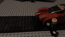 a red hot wheels car is sitting on a lego surface