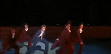 a group of people in suits are dancing on a stage in a dark room .