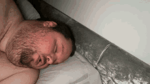 a man with a beard is sleeping with his head on a pillow