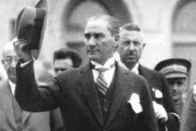 a man in a suit and tie holds a hat in his hand