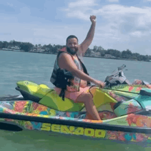 a man is sitting on a jet ski in the water with his hand in the air .