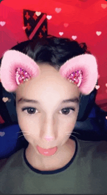 a young boy wearing a snapchat filter with cat ears on his face .