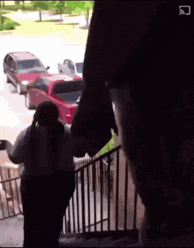 a man and a woman are walking down stairs with a red truck in the background