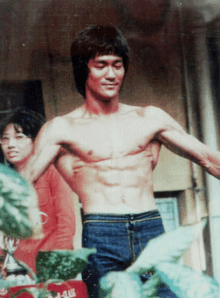 a man without a shirt is standing in front of a coca cola container