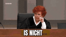 a judge is sitting at a desk in a courtroom with a sign that says `` is nicht '' .