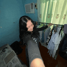 a woman is standing in front of a window holding a clothes rack