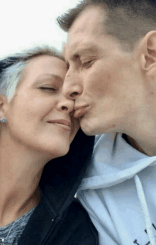 a man kisses a woman on the forehead while wearing a white sweatshirt