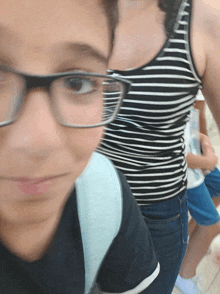 a woman in a striped tank top is standing next to a boy wearing glasses