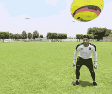 a soccer player in a white shirt with the word audi on it stands in front of a yellow soccer ball