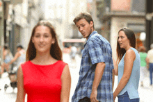 a woman in a red dress is looking at a man in a blue plaid shirt walking down the street .