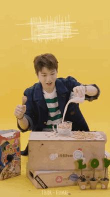 a young man is pouring milk into a cup of cereal while sitting in front of a box that says saturday