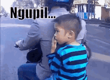 a little boy is sitting on the back of a person on a motorcycle with the words ngupil written on the bottom