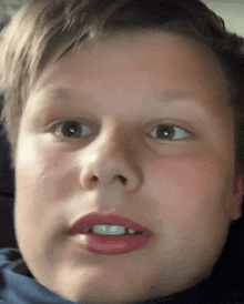 a close up of a young boy 's face with a blue shirt