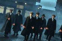 a group of men in suits and hats are walking down a street with their hands painted red