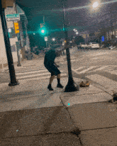 a man squatting on a sidewalk in front of a street sign that says ' stevens ave ' on it