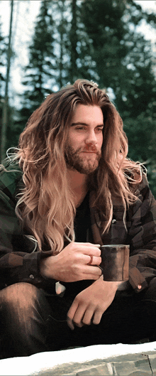 a man with long hair and a beard holding a cup