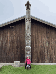 two children standing in front of a totem pole that says ' a ' on it