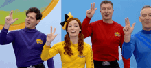 a woman in a yellow shirt with the word wiggles on it stands between two men