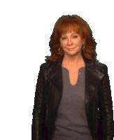 a woman with red hair is wearing a leather jacket