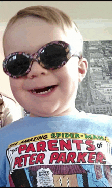 a young boy wearing sunglasses is wearing a shirt that says " the parents of peter parker "