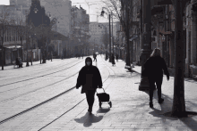 a woman wearing a mask pushes a shopping cart down a busy street