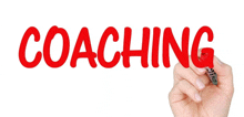 a person is writing the word coaching with a red marker