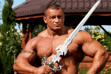 a shirtless man is holding a sword with a design on it