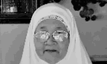 a black and white photo of an elderly woman wearing glasses and a white veil .