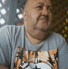 a man with a beard is wearing a shirt with palm trees and a star on it