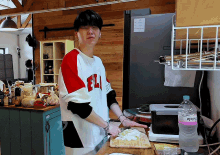 a man in a red white and black shirt with the letter fl on it is cutting vegetables on a cutting board