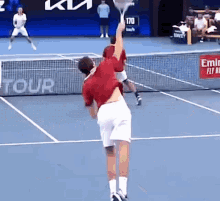 a man is holding a tennis racquet on a tennis court with emirates written on the side of the net