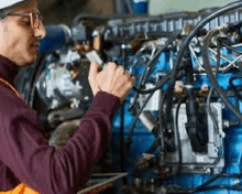 a man in a hard hat is working on a blue engine .